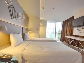 A hotel room with two beds, a TV, and a window with curtains.