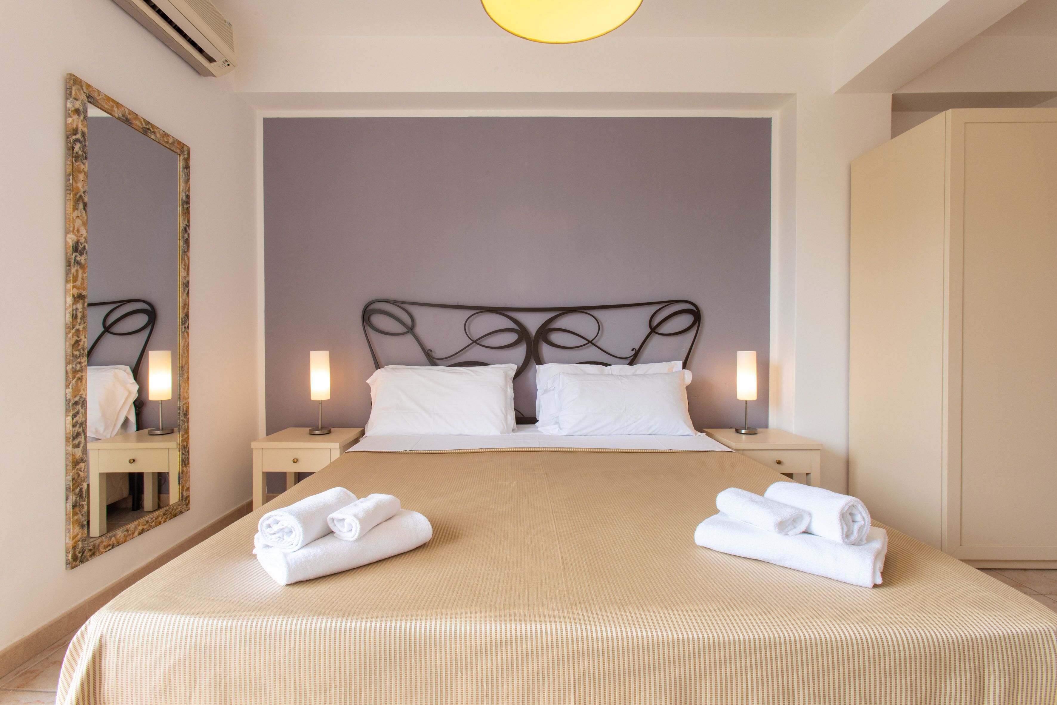 Una cama bien hecha con sábanas blancas y dos toallas enrolladas sobre la cama.