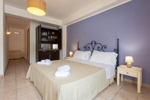Une chambre à coucher avec un lit, des tables de chevet, une armoire et une salle de bain visible au fond.