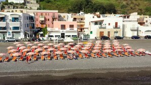 Une zone située au bord de la plage, avec de nombreux parasols et des chaises longues disposés en rangées.