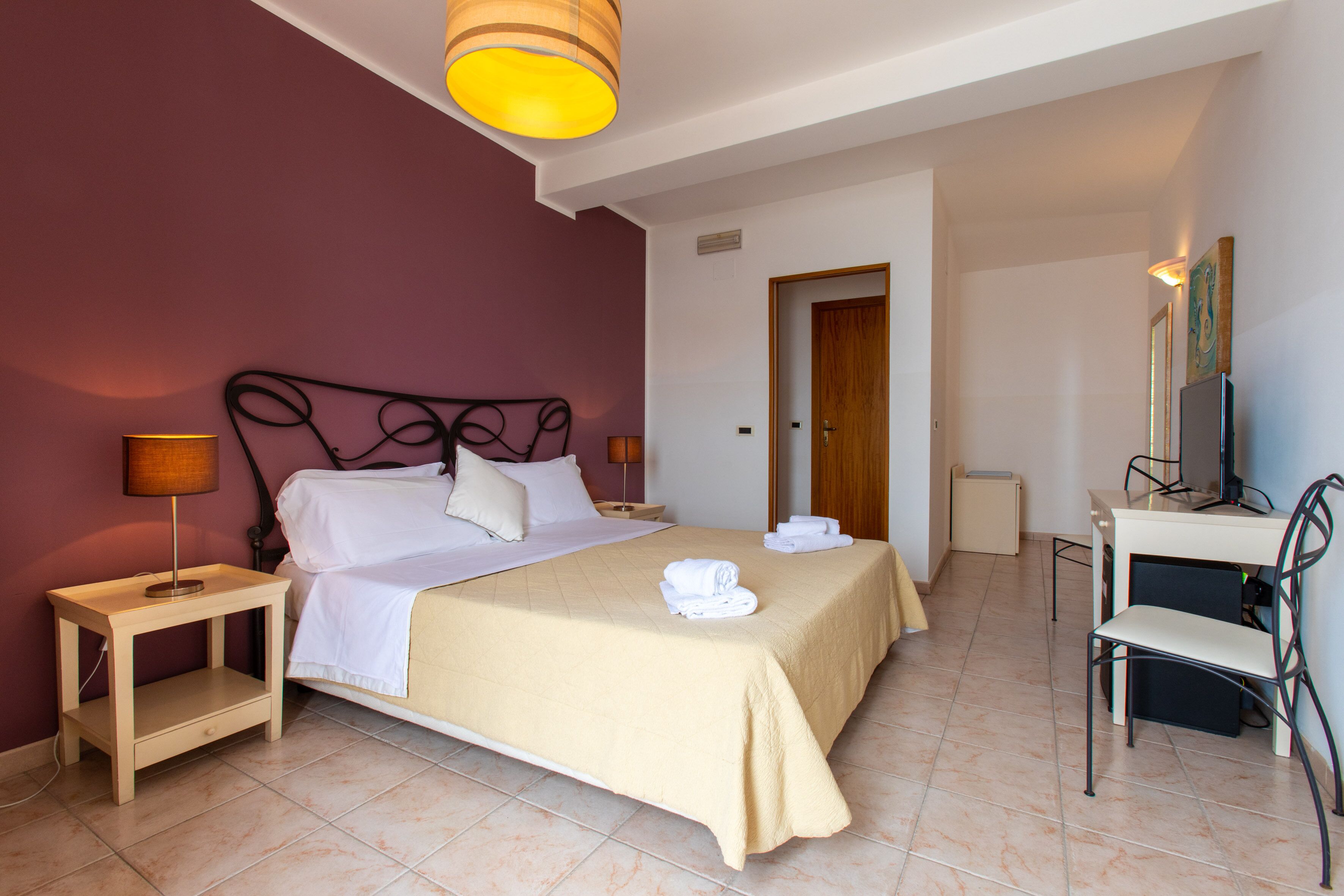 A hotel room with a bed, bedside tables, a desk, and a chair.