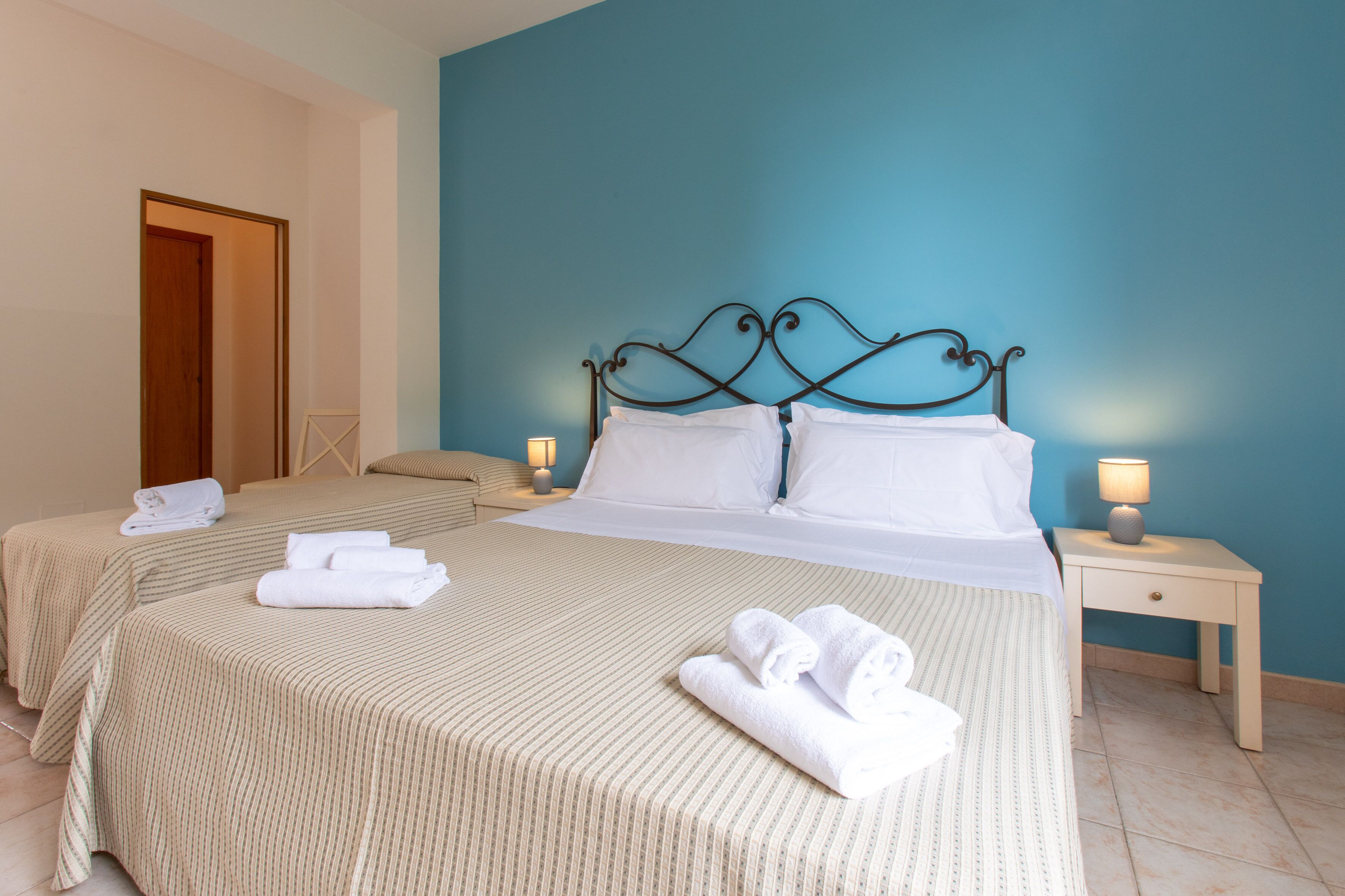 A hotel room with two beds, each with a striped bedspread and white pillows, and a nightstand with a lamp.