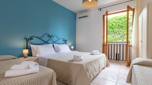Une chambre d’hôtel avec deux lits, un mur d’accent bleu, un balcon avec une balustrade et un appareil de climatisation.