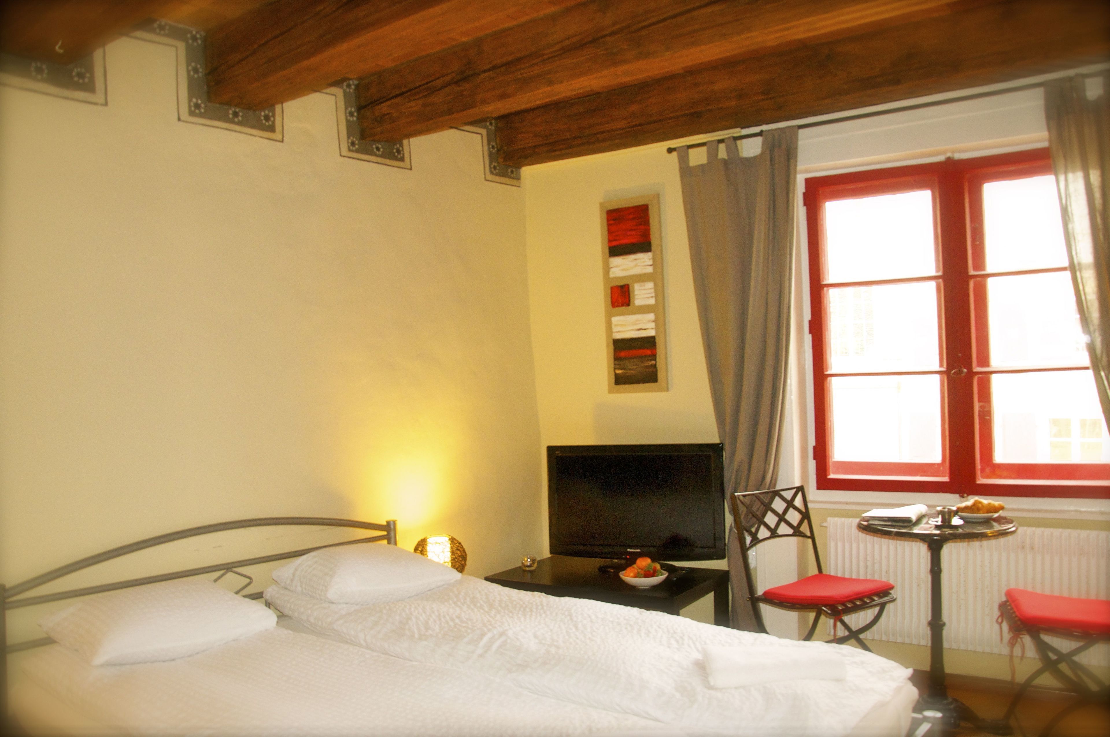 Habitación de hotel con cama, televisión, una mesita con un frutero y una silla.