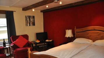 Ein Hotelzimmer mit einem hölzernen Bett, einem roten Sessel, einem Fernseher und einer roten Wand.