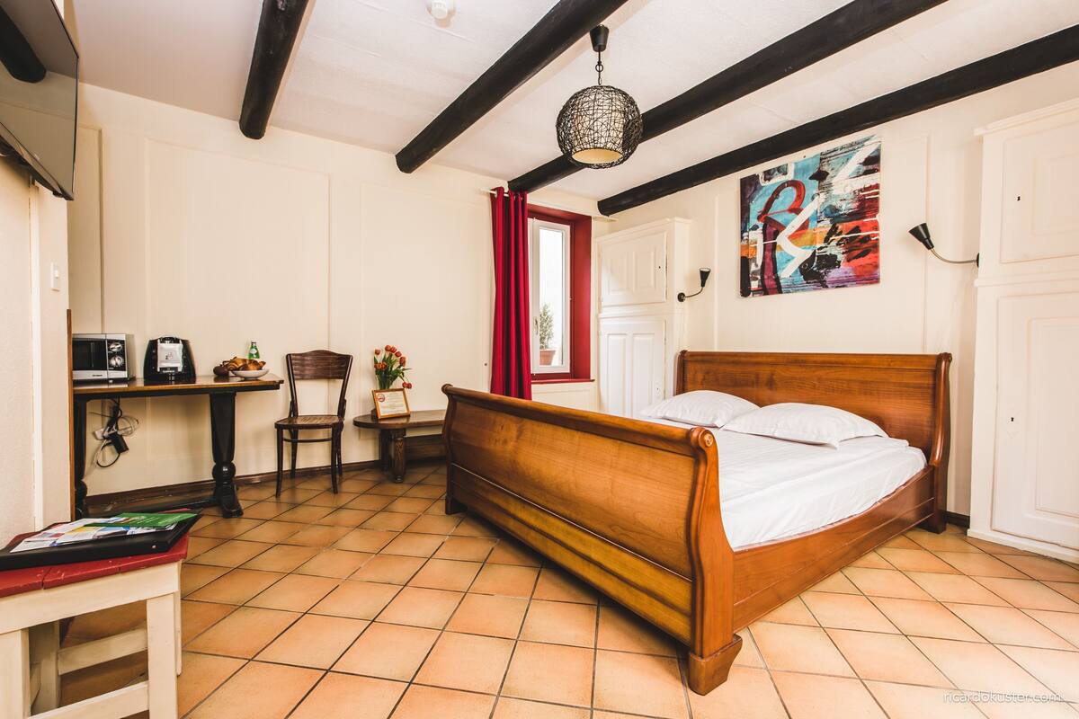 Un dormitorio con una cama de madera, un escritorio con una computadora, una silla y una cortina roja.