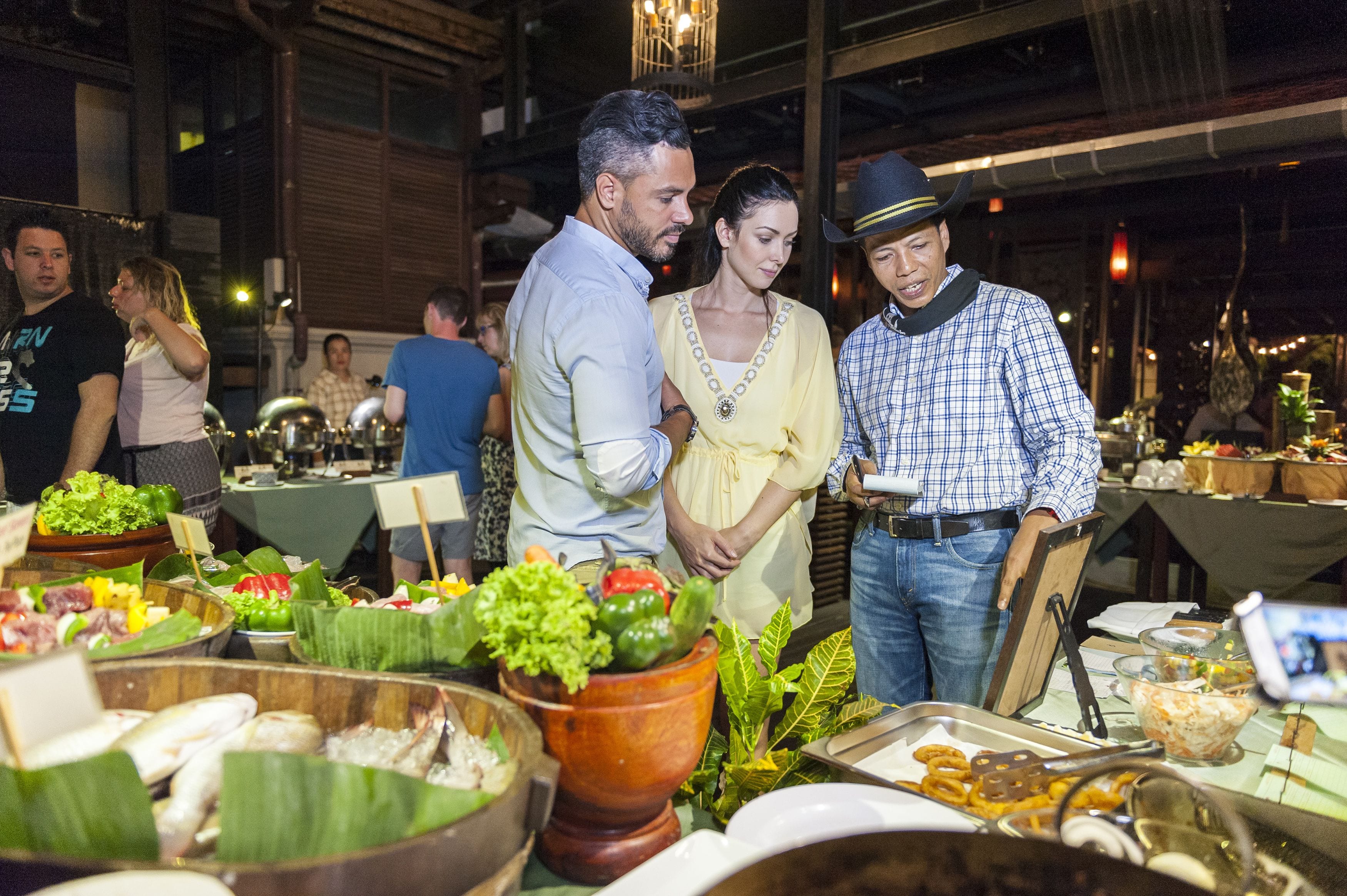 A buffet with various dishes and a group of people standing around.