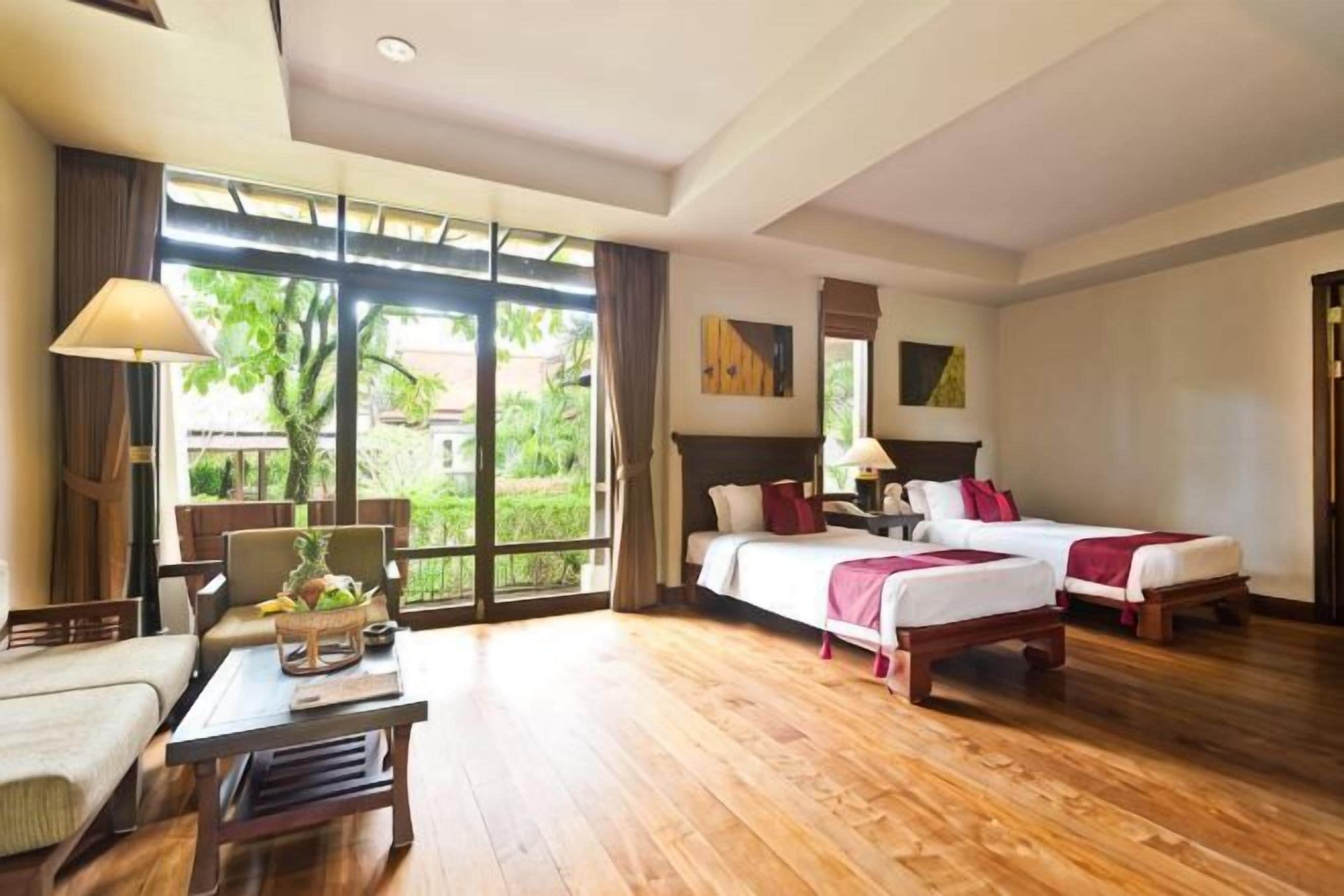 A hotel room with two beds, a desk, and a large window.