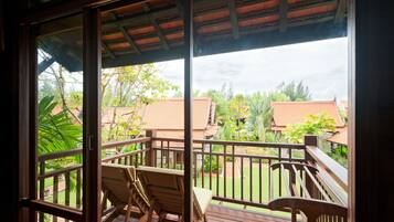 A wooden deck with a railing, two wooden chairs, and a view of a residential area with houses and greenery.