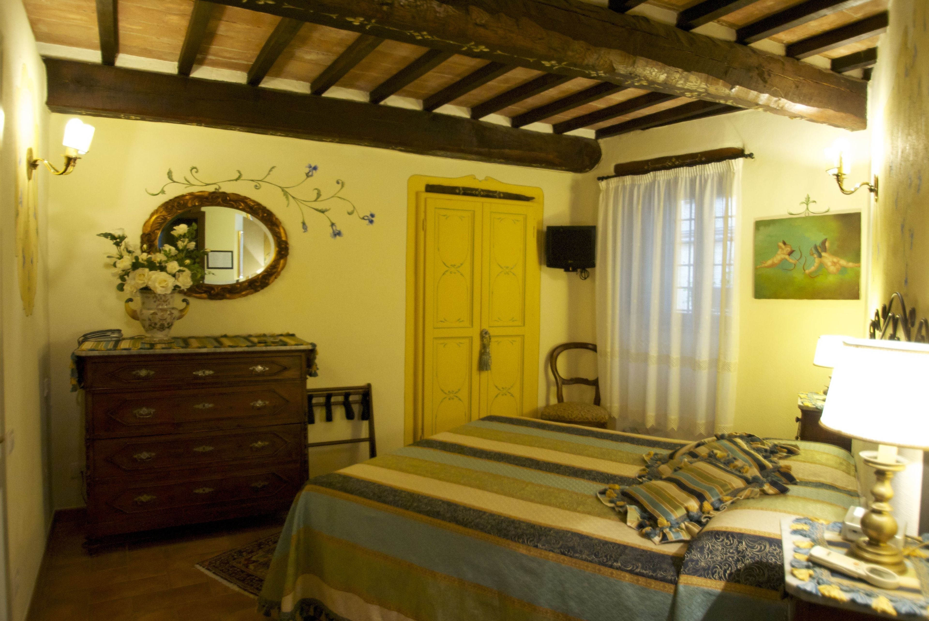 Un dormitorio con cama, cómoda, espejo, puerta amarilla y un cuadro en la pared.