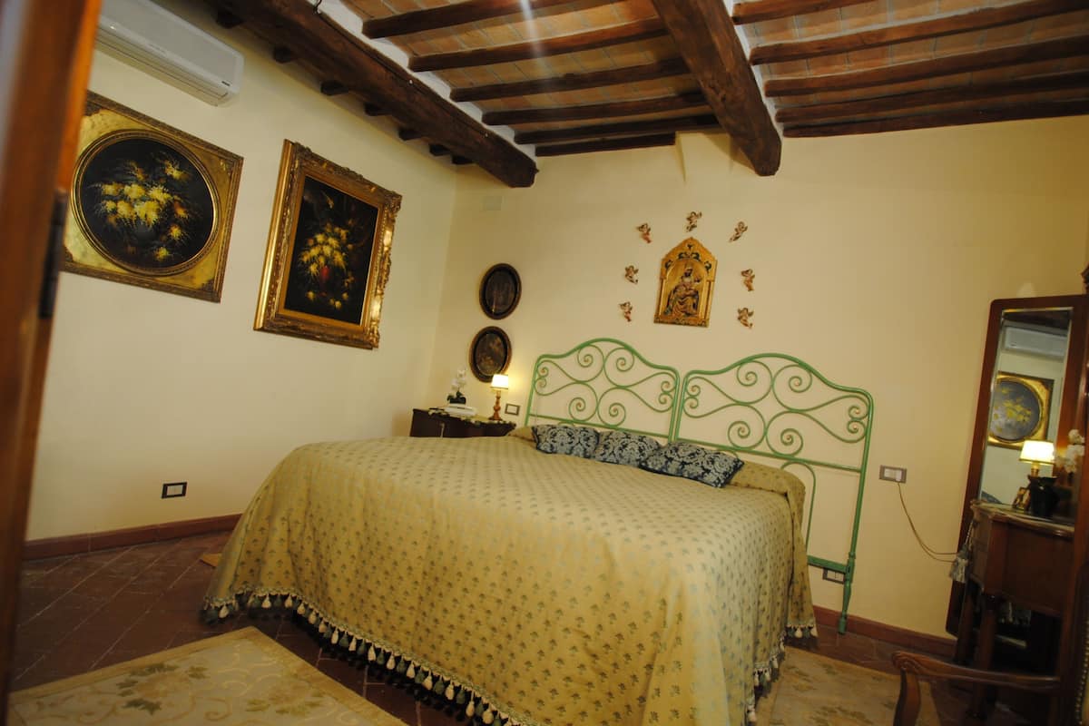 A bedroom with a bed, a nightstand, a mirror, and wall decorations.