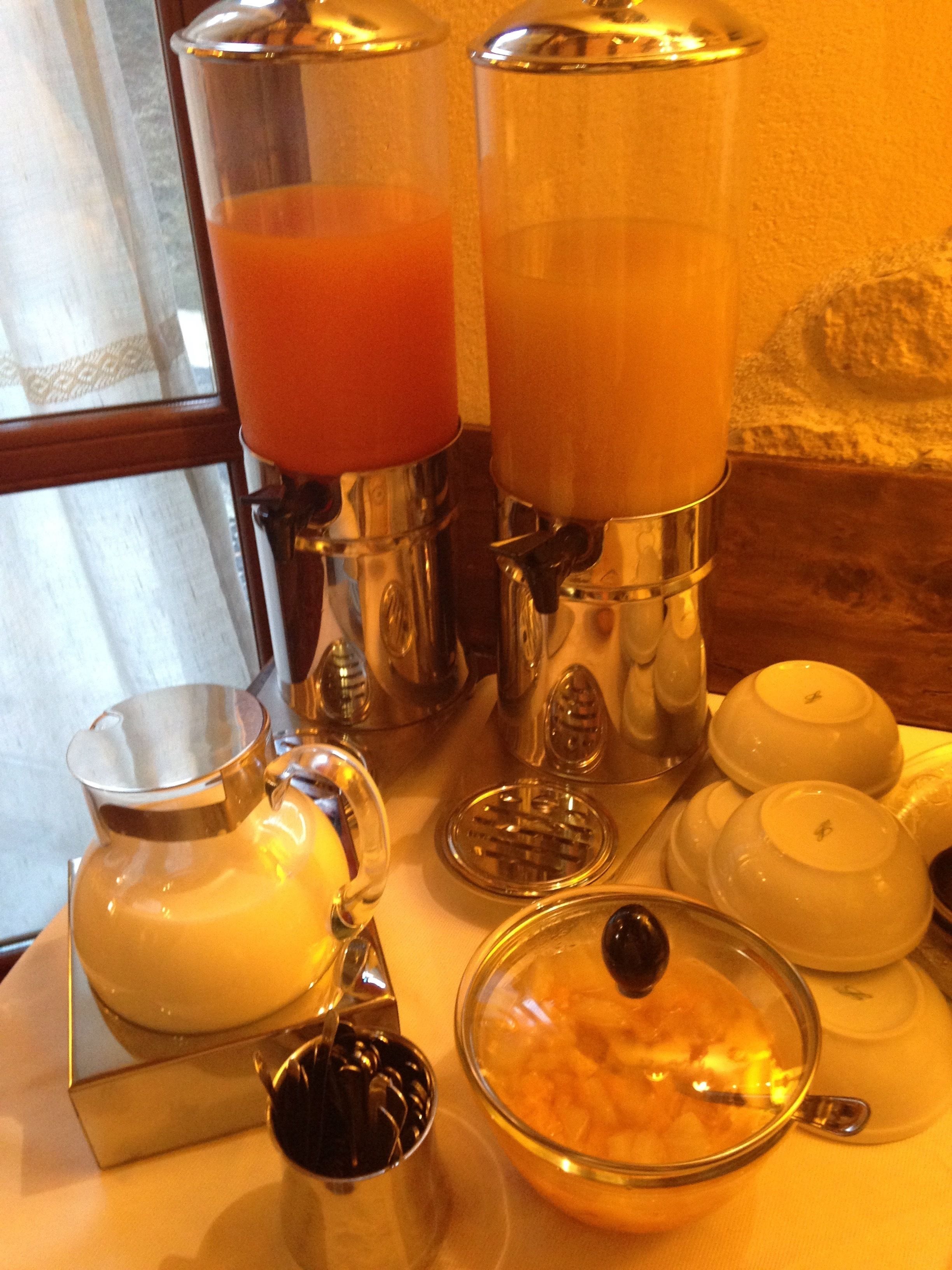 A breakfast setup with a pitcher, a glass bowl, and a teapot on a table.
