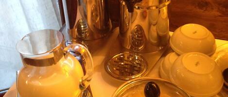 A breakfast setup with a pitcher, a glass bowl, and a teapot on a table.