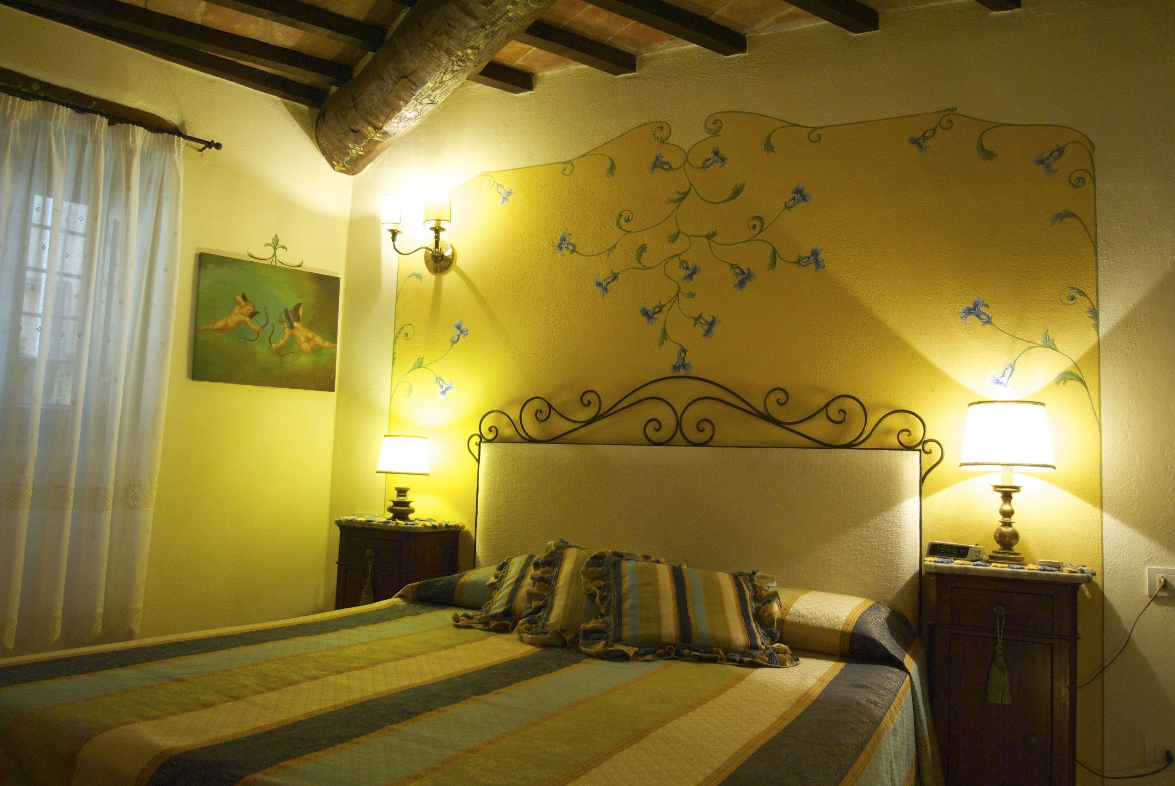 Habitació d'hotel amb un llit, dues taules de nit, una paret amb paper pintat floral i un quadre penjat a la paret.
