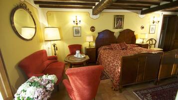 Ein traditionell eingerichtetes Schlafzimmer mit einem hölzernen Bett, einem roten Sessel, einem kleinen Tisch mit Lampe und einem Spiegel an der Wand.