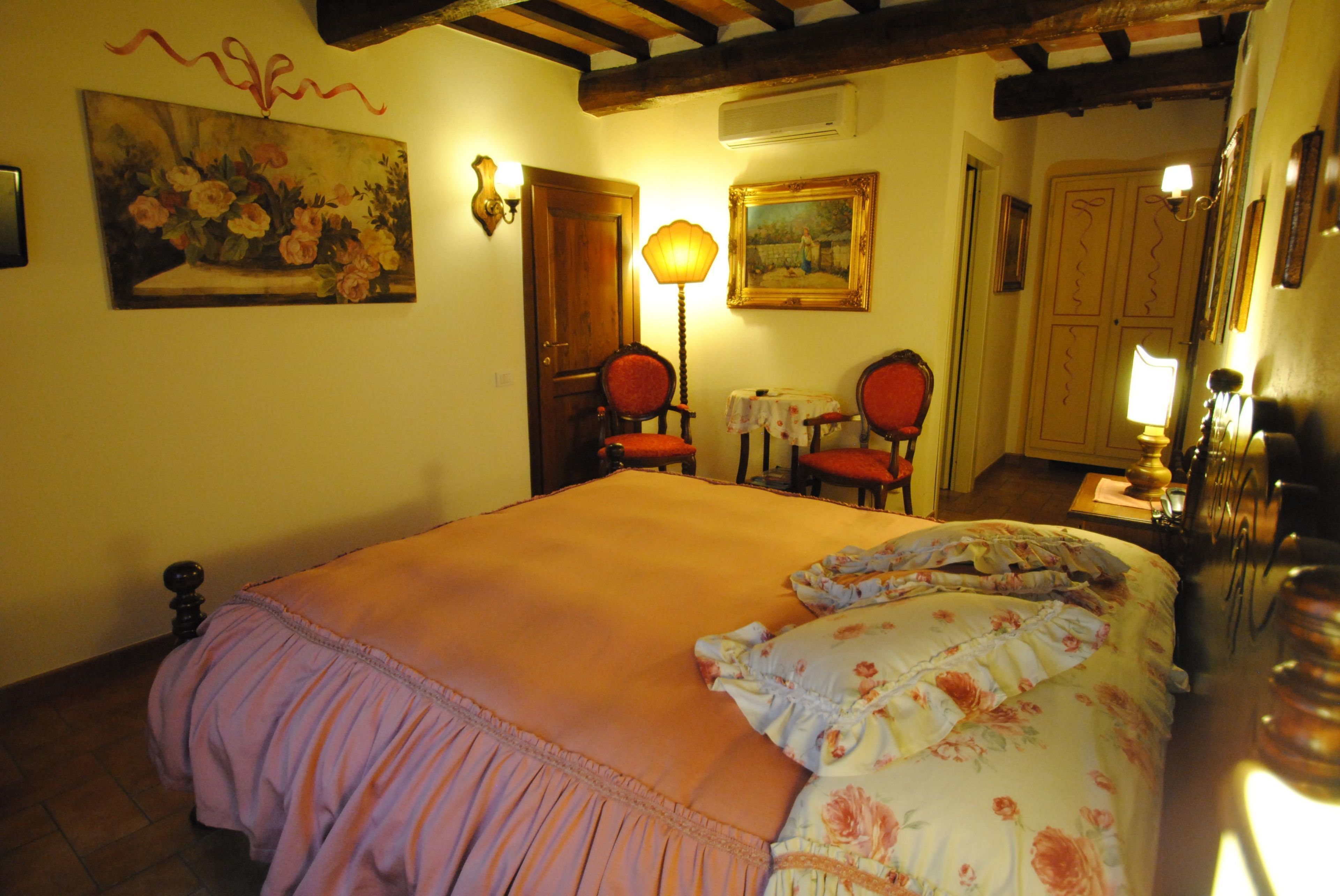 Un dormitorio con una cama grande, techo de madera, un cuadro, una lámpara y una puerta.