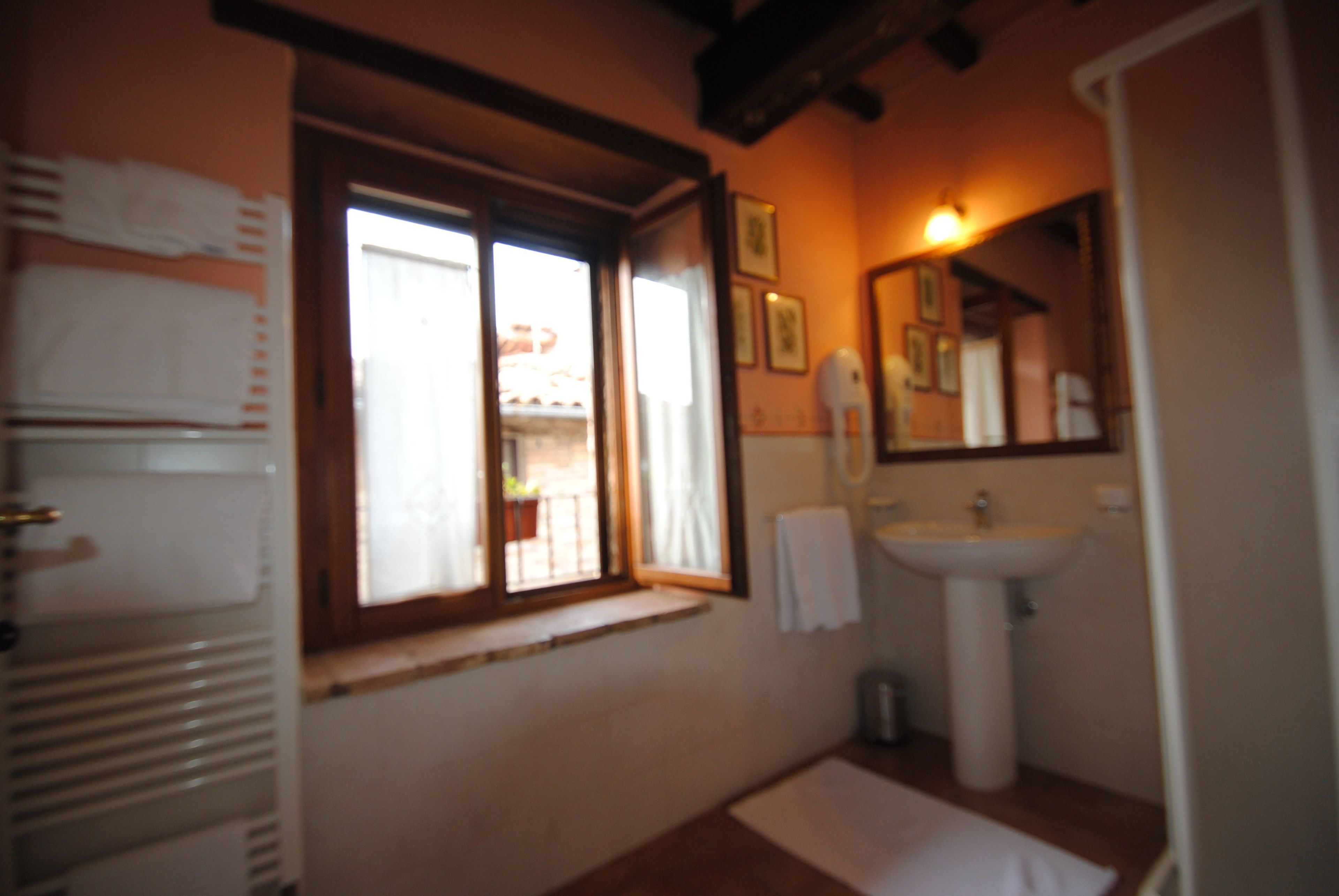 Ein Badezimmer mit Fenster, Waschbecken und Spiegel.