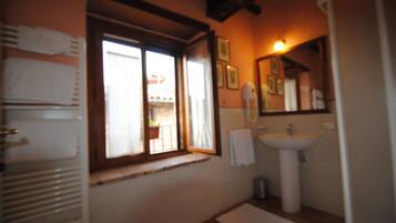 Ein Badezimmer mit Fenster, Waschbecken und Spiegel.