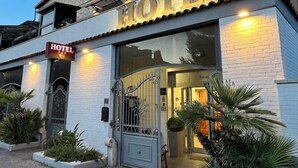 A hotel with a stone facade, a large entrance gate, and potted plants in front. - E H ROME AIRPORT (Fiumicino)