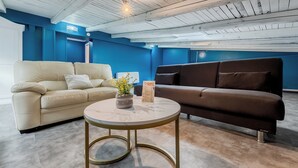 A modern living room with a beige sofa, a dark brown sofa, and a round coffee table with a marble top. - E H ROME AIRPORT (Fiumicino)