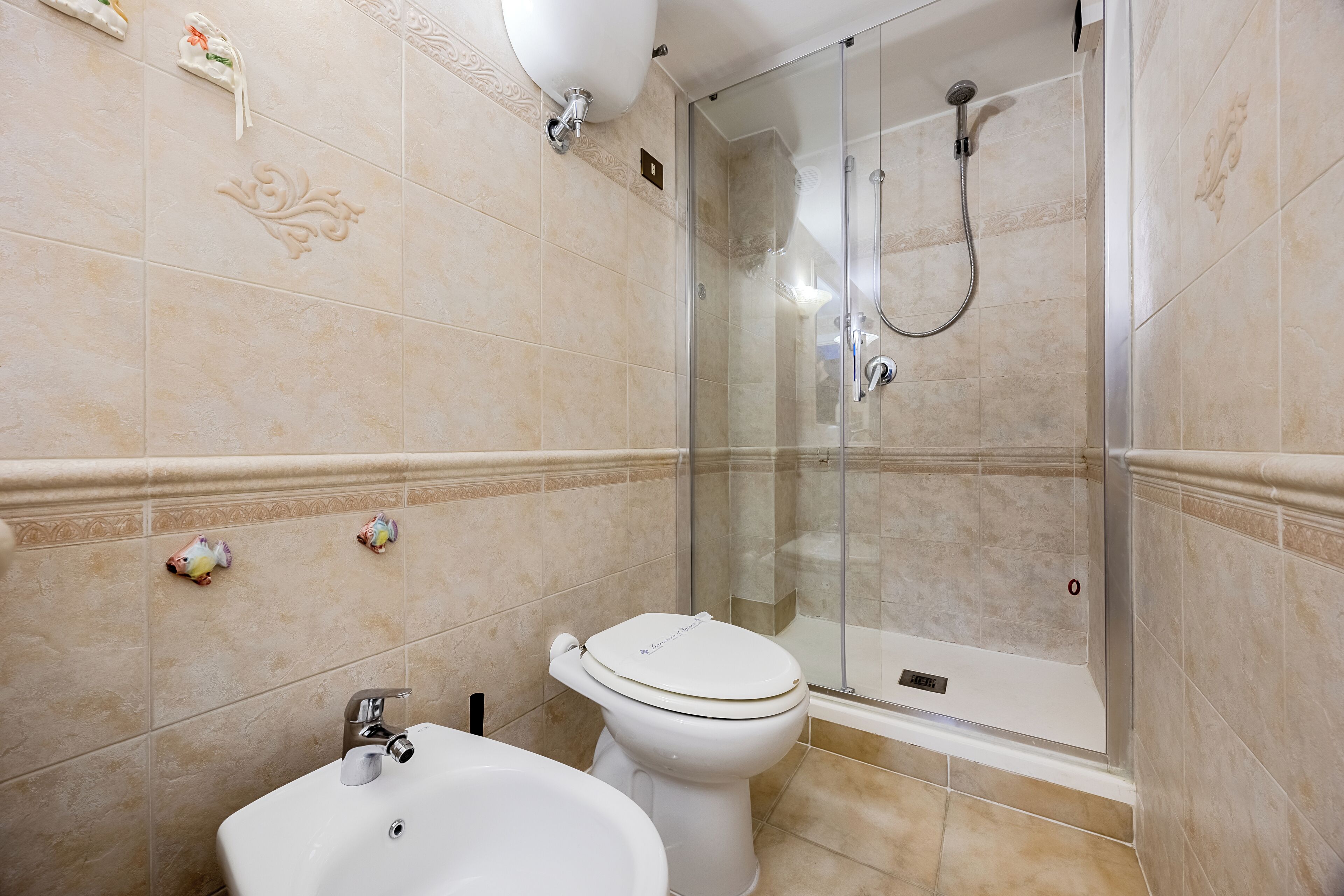 Une salle de bain équipée de toilettes, d’un lavabo et d’une douche à parois de verre.