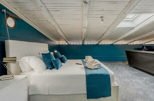 Un dormitorio con cama, lámpara de noche y pared azul.