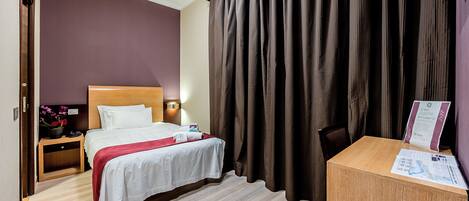 Una habitación de hotel con una cama, mesita de noche y un escritorio con silla.