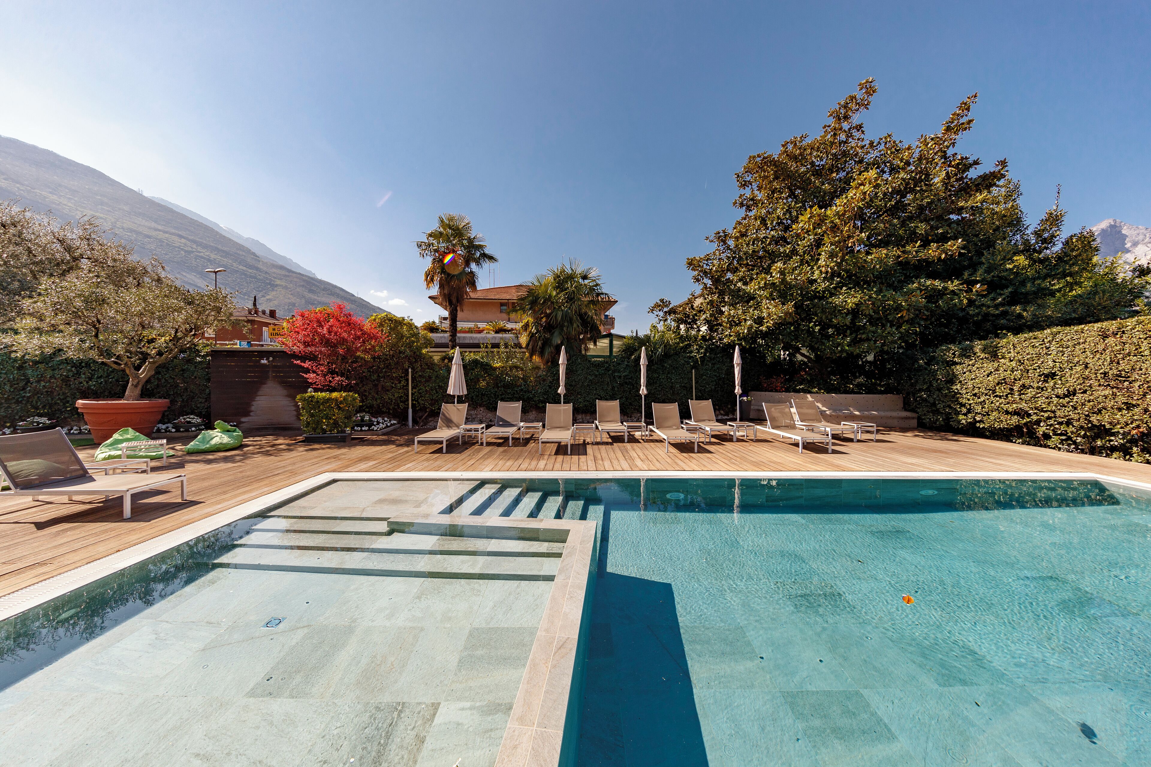 Une piscine avec des chaises longues et une terrasse en bois.