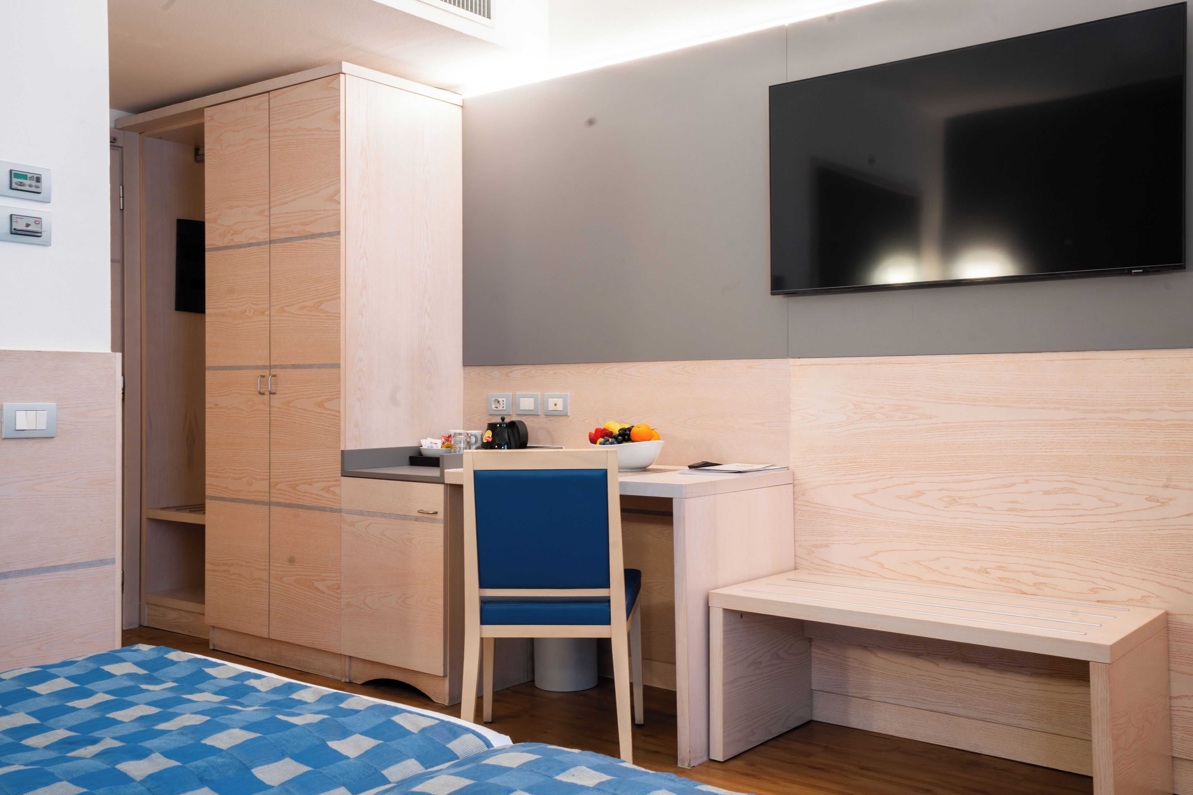 Une chambre à coucher comprenant un lit, un bureau, une chaise, une armoire et un téléviseur.
