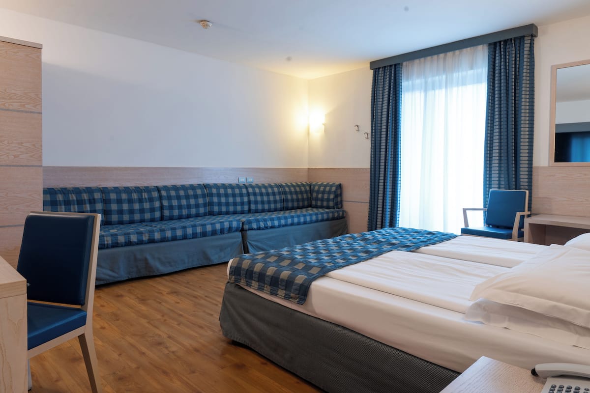 A hotel room with a bed, a sofa, a chair, and a desk.