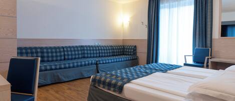A hotel room with a bed, a sofa, a chair, and a desk.