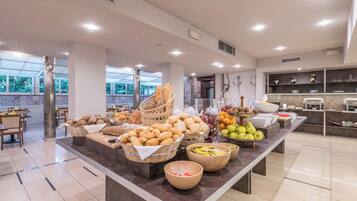 A buffet area with bread, fruits, and beverages.