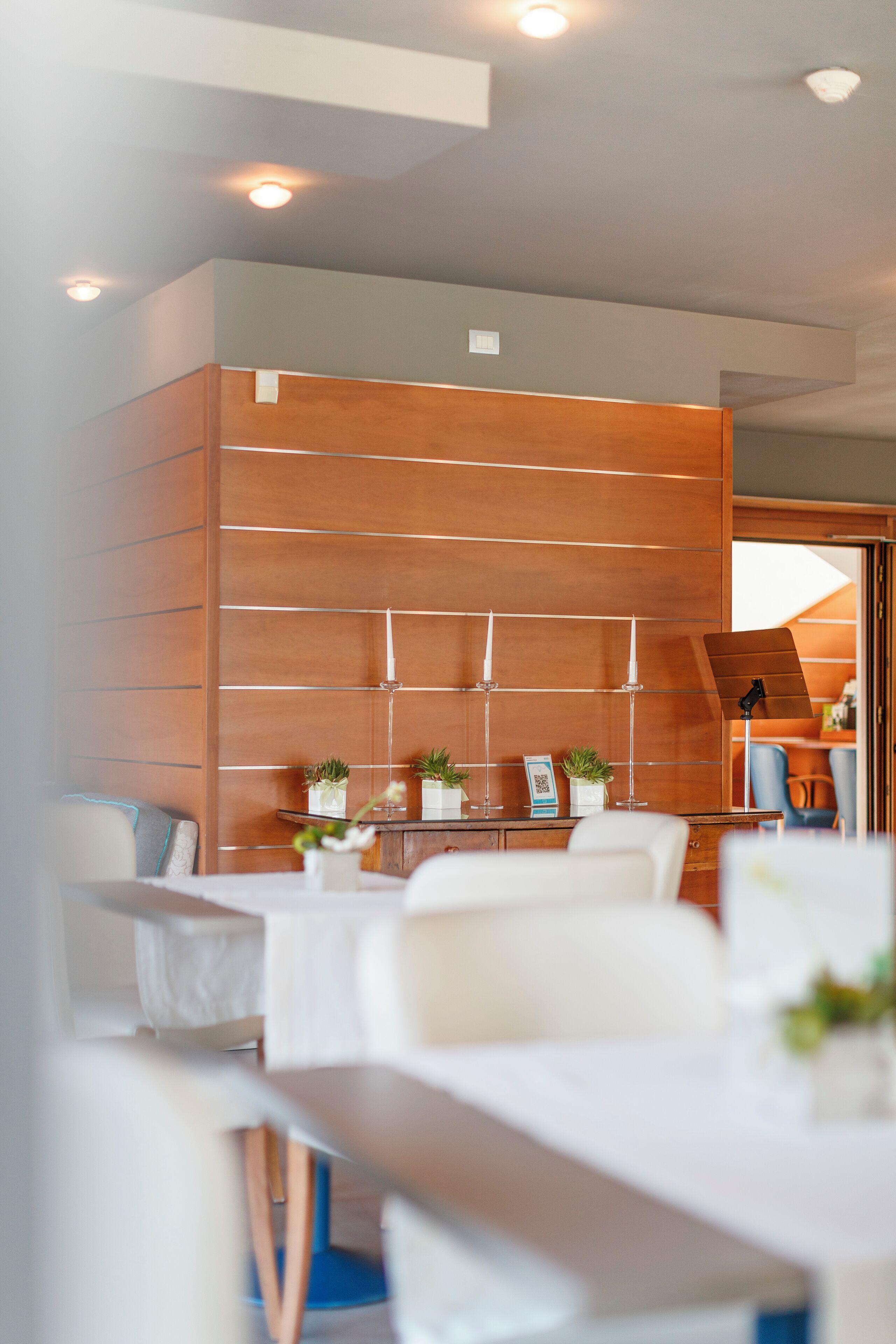 A modern interior with a wooden panel wall, white furniture, and small plants.