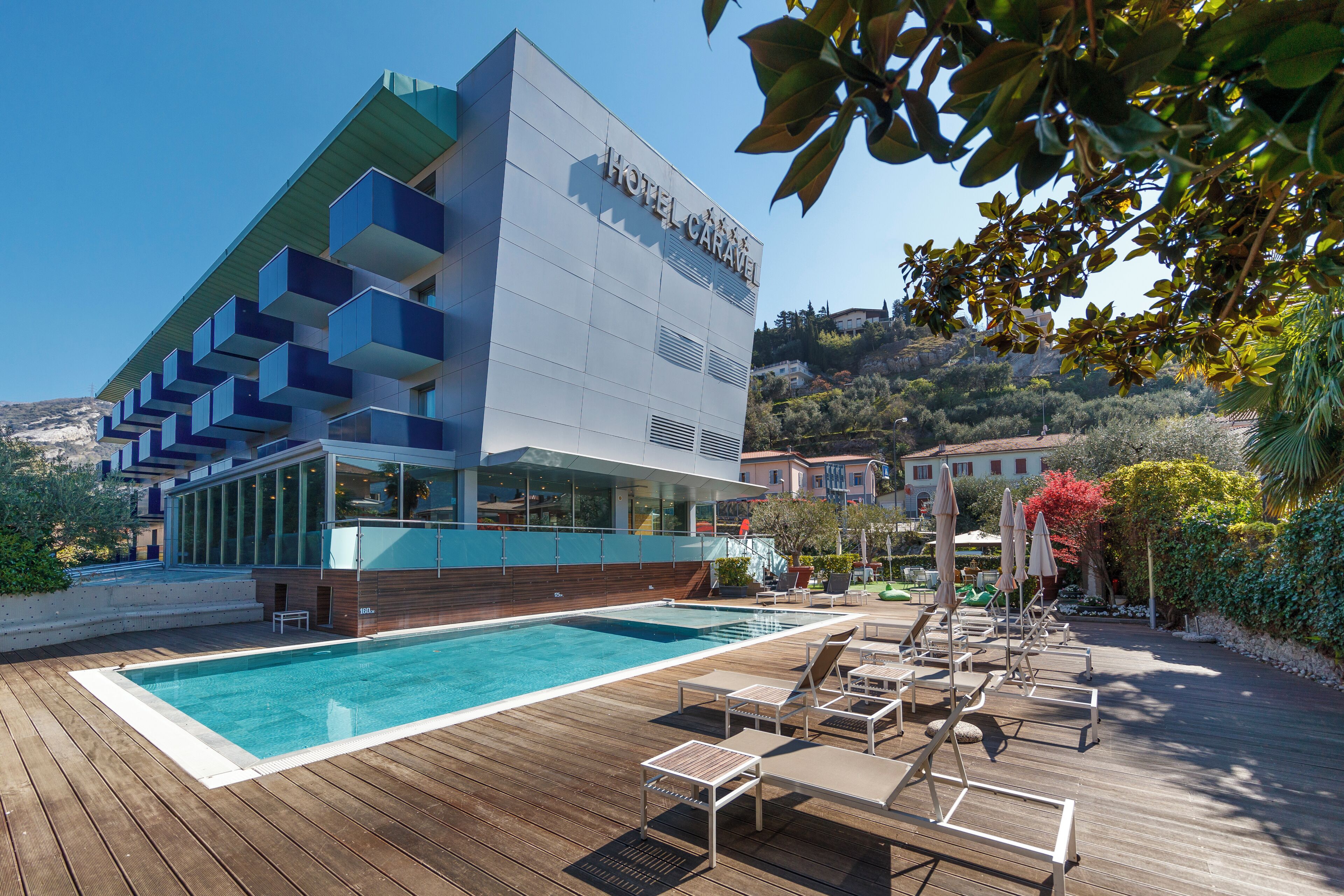 A modern hotel with a pool area, lounge chairs, and a view of the surrounding landscape.