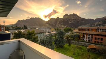 Un balcon offrant une vue sur les montagnes et les bâtiments au coucher du soleil.