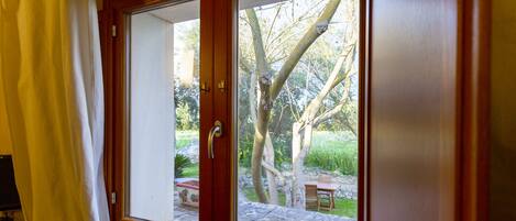 A sliding glass door leading to an outdoor patio with a stone table and chairs, surrounded by trees.