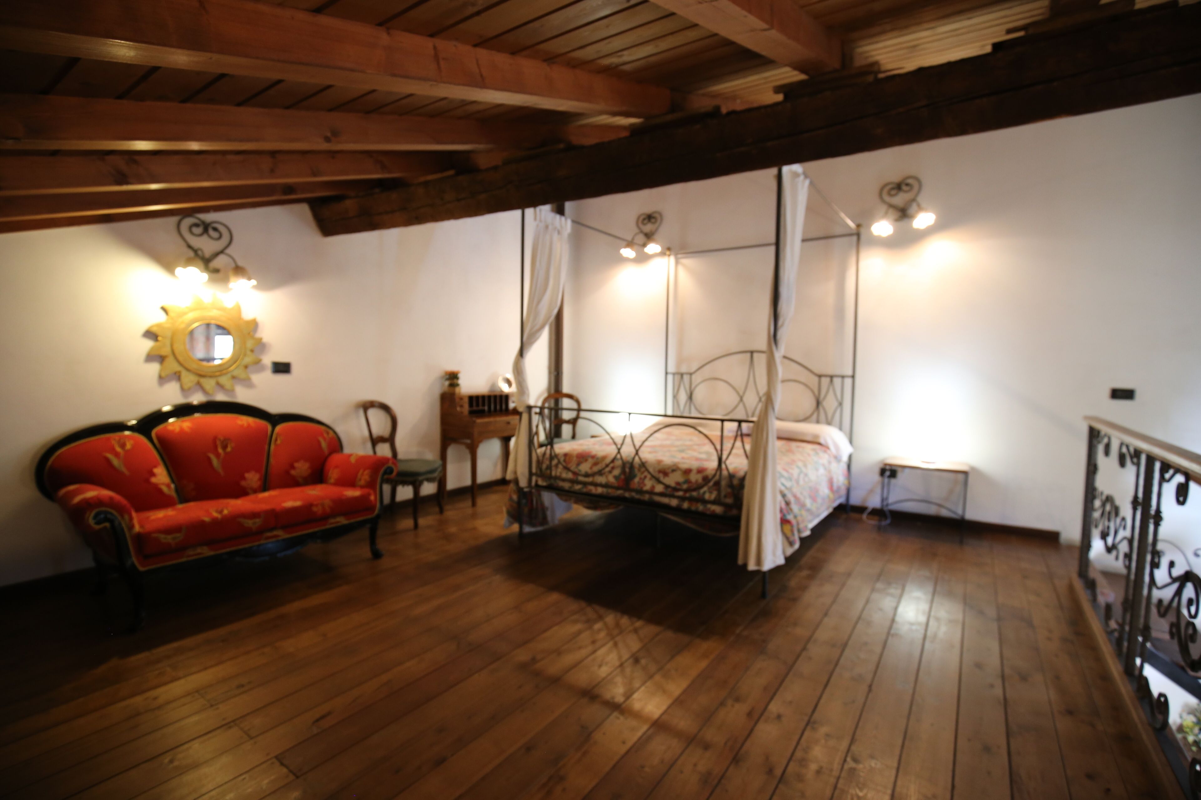 Un dormitorio con cama con dosel, un sofá rojo y techo de madera.