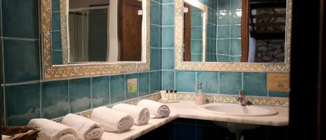 Une salle de bain avec des carreaux turquoise, un lavabo blanc et deux miroirs dotés de cadres décoratifs.