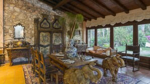 Una habitación con pared de piedra, muebles de madera, un jarrón grande y una estatua de elefante.