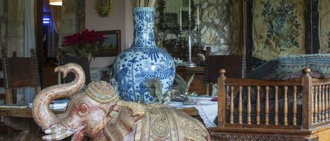 A room with a large blue vase, a wooden bench, and a decorative elephant statue.