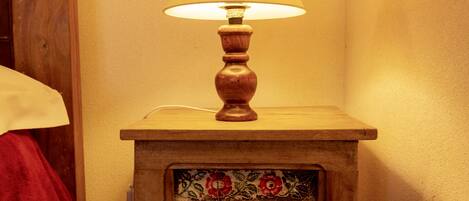 A wooden bedside table with a lamp and a decorative panel.