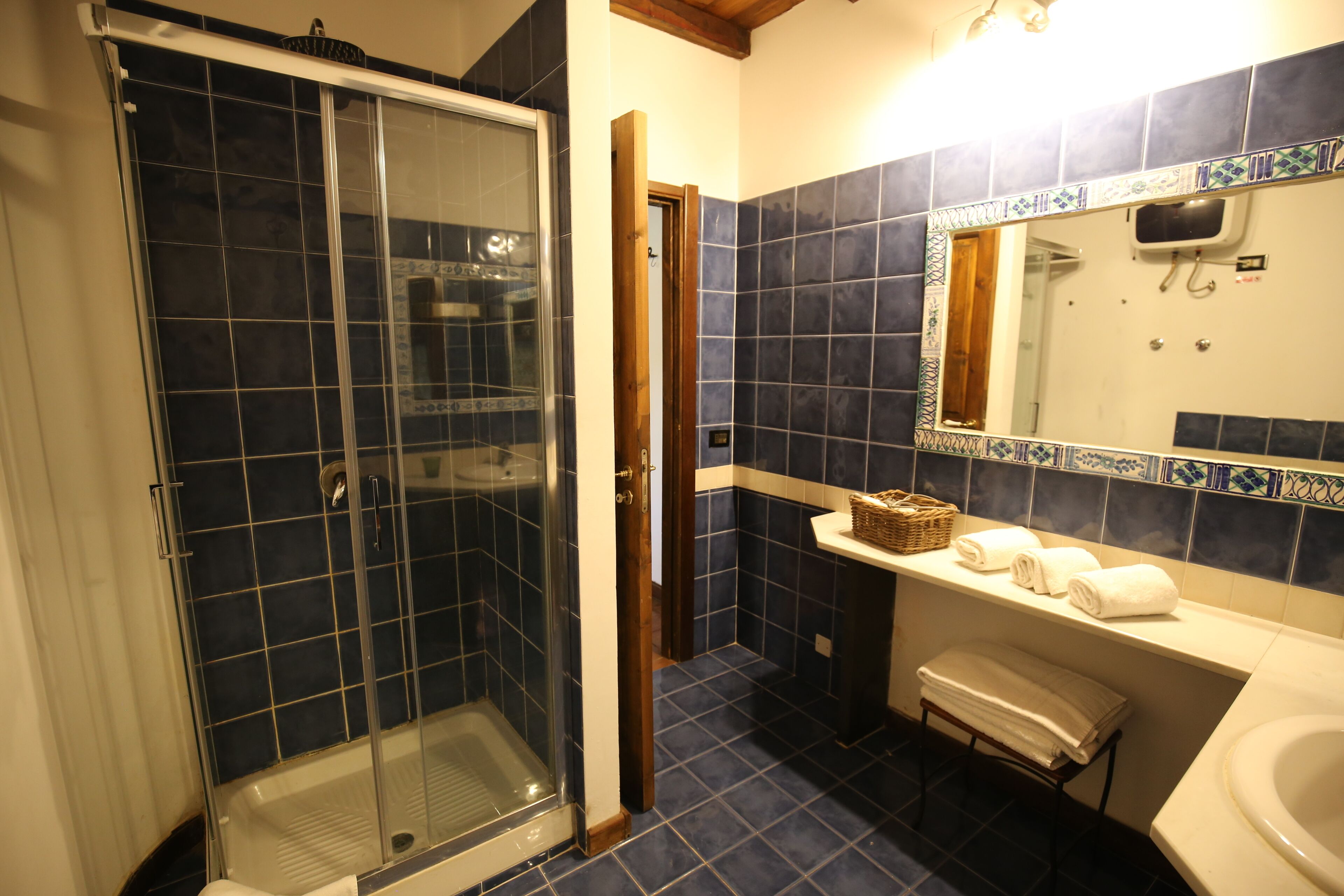 Un baño con ducha de vidrio, lavamanos blanco y espejo sobre él.