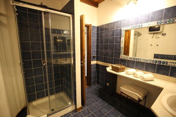 A bathroom with a glass-enclosed shower, a white sink, and a mirror above it. - Villa Dei Papiri (Syracuse)