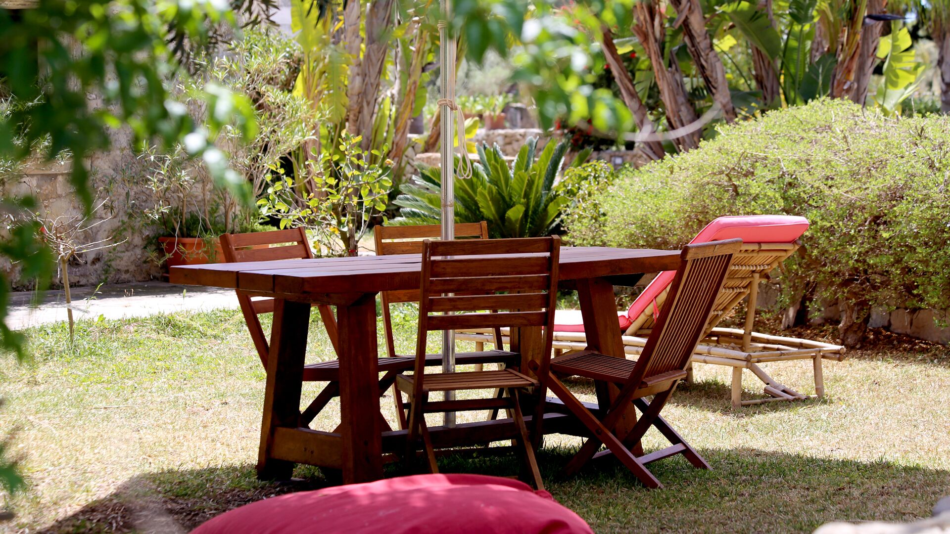 Un ensemble de mobilier de jardin en bois, comprenant des chaises et une table, entouré de verdure et de plantes.