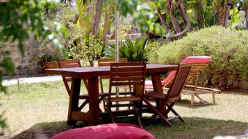 Un ensemble de mobilier de jardin en bois, comprenant des chaises et une table, entouré de verdure et de plantes.