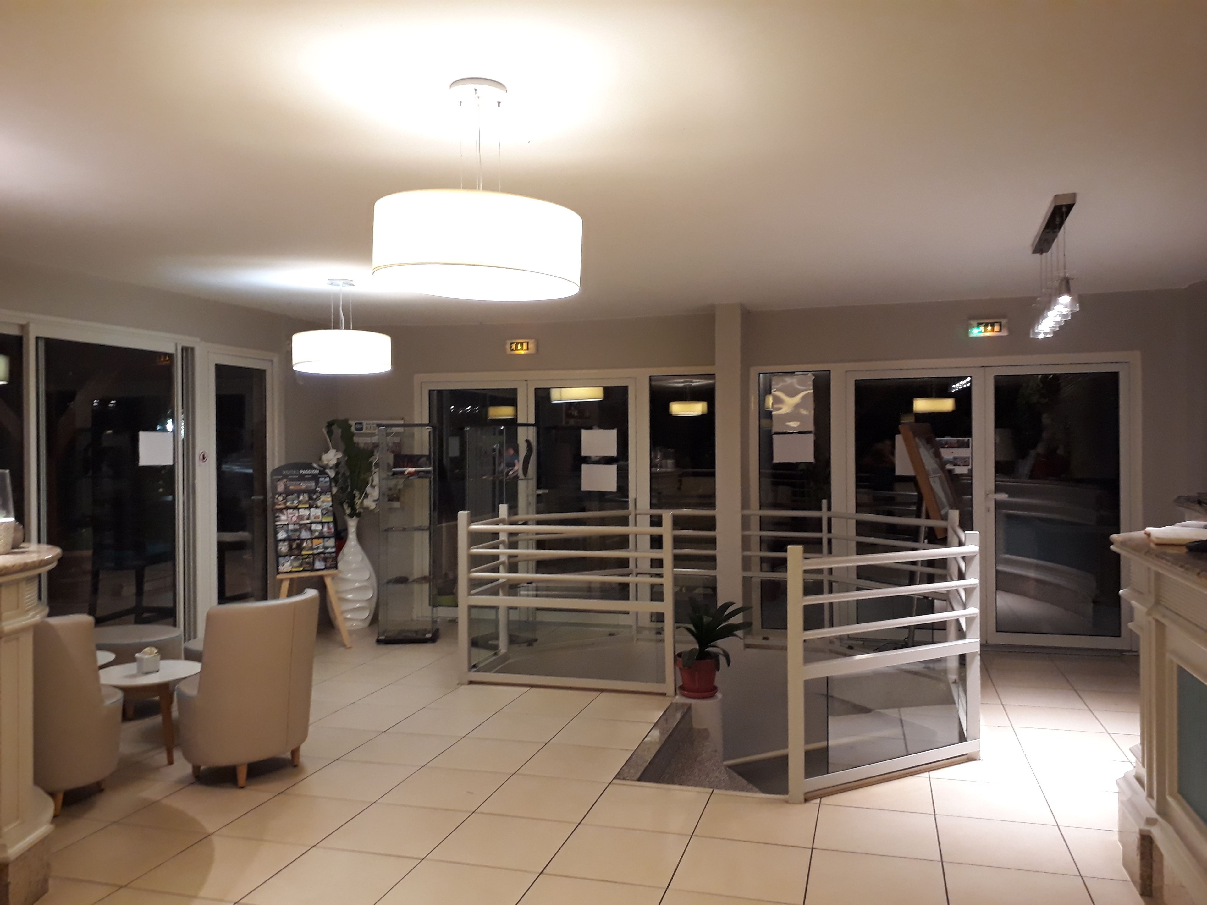 Um hall de hotel com balcão de recepção, área de estar e divisória de vidro.