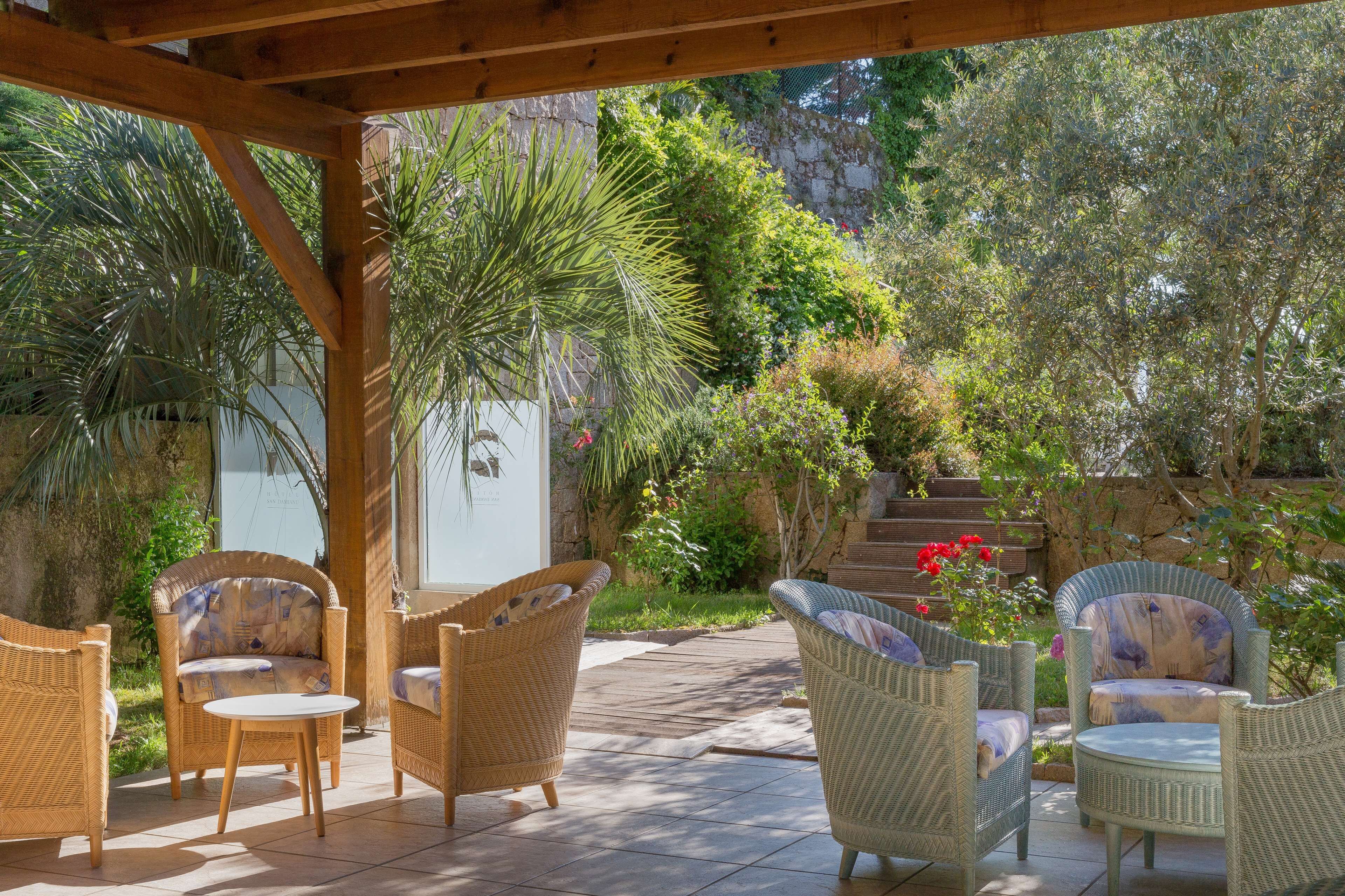 A covered patio area with wicker furniture, a small table, and a potted plant.