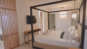 Una habitación de hotel moderna con una cama con dosel, un televisor de pantalla plana en la pared y un escritorio de madera.