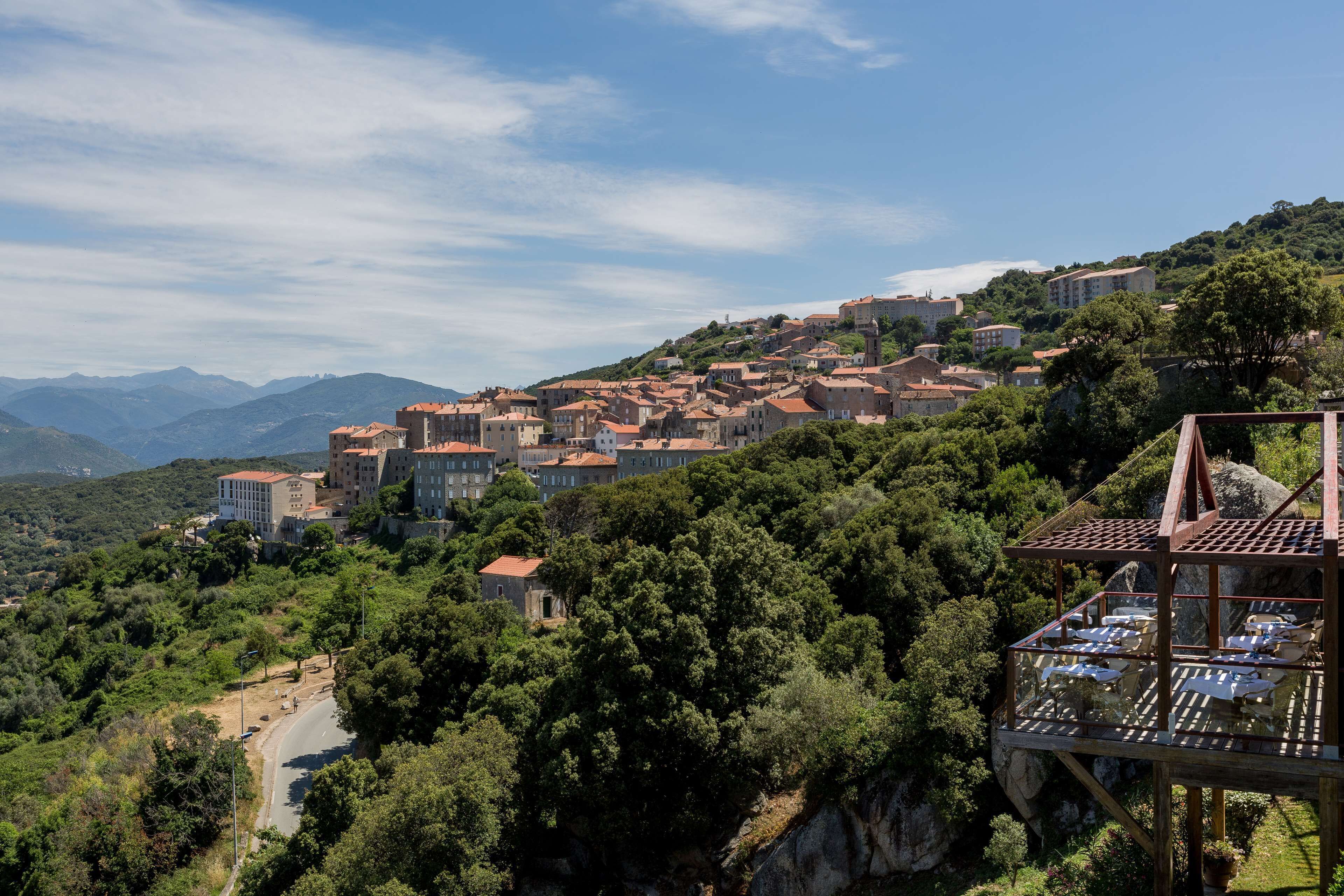 A hillside town with buildings, a road, and a wooden structure with a roof.
