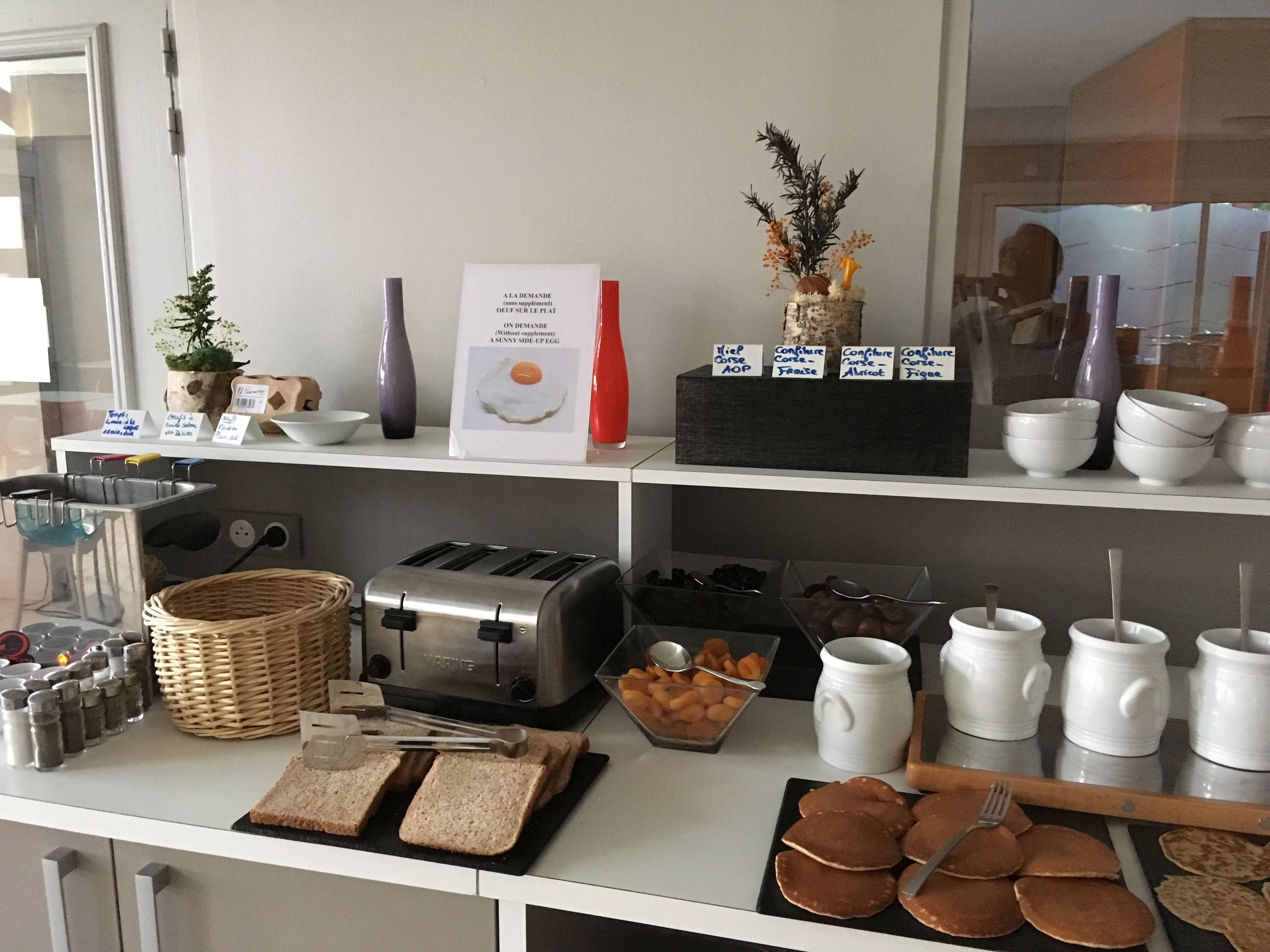 A breakfast buffet setup with various food items, a toaster, and condiments.